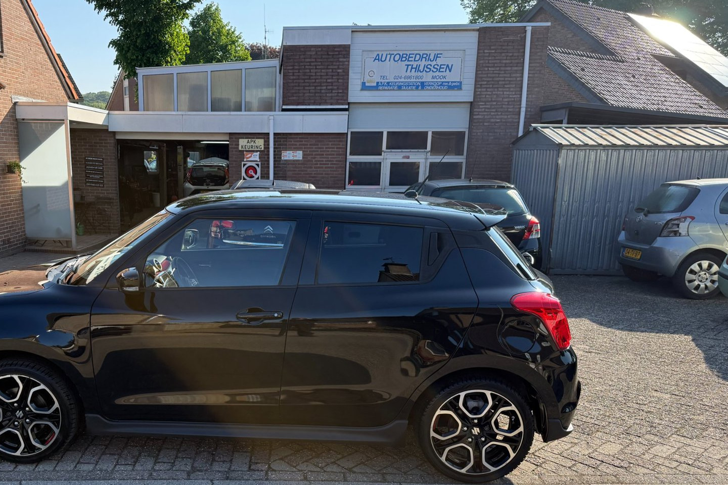 De werkplaats van Autobedrijf Thijssen met het bord "A.P.K. keuringstation, verkoop nw. en gebr., reparatie, taxatie en onderhoud"
